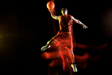 Unstoppable. African-american young basketball player of red team in action and neon lights over...