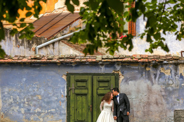 Beautiful wedding couple posing in front ol old house