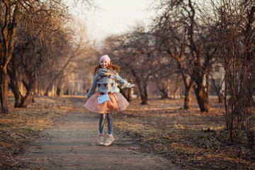 Fototapeta premium Happy red-haired girl with freckles in a sunny park. Spring or Autumn. Happy carefree childhood.