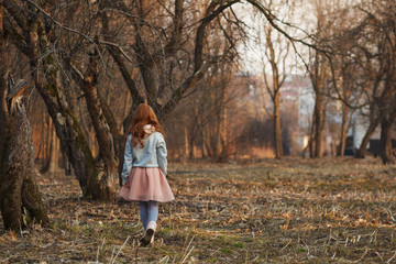 Red-haired girl with freckles in a park. Spring or Autumn. Happy carefree childhood.