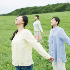 草原で深呼吸をする3人の女性