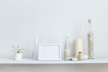 Shelf against white wall with decorative candle, glass and rocks. Potted spider plant.