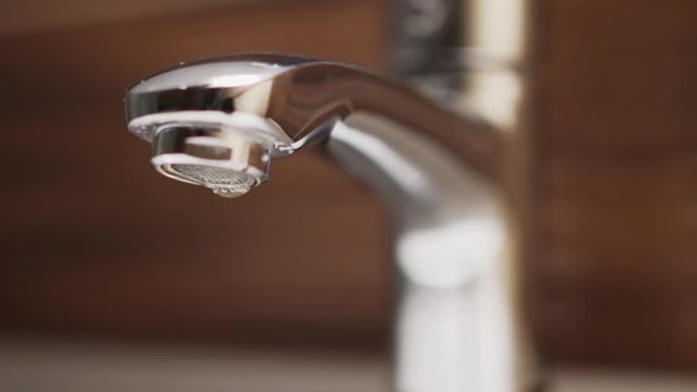 Dripping tap in bathroom. Water waste in slow motion.