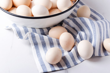 Uncooked eggs just collected on the farm.Lot of eggs in the boel and on the napkin.Kitchen table...