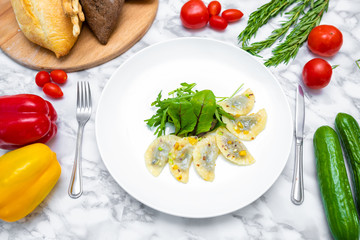 Dumplings, filled with cabbage. vegetable dumplings. Dumplings with potatoes in plate on white background. Ingredients for dumplings with cabbage, potatoes, tomato, cucumber, lettuce, pepper. Top vie