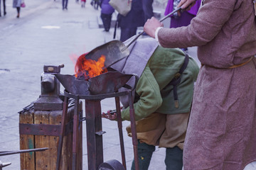 Blacksmith workshop on the street. People in traditional clothses forge metal