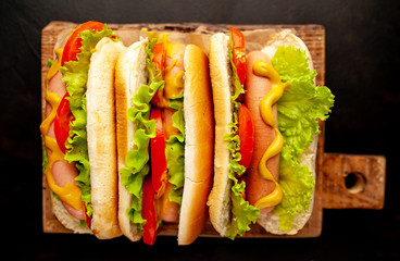 three hot dogs on a cutting board against a background of stone