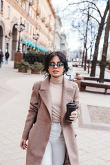 Fototapeta premium Beautiful woman holding paper coffee cup and enjoying the walk in the city