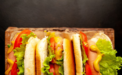 three hot dogs on a cutting board against a background of stone