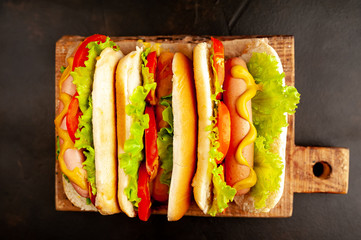 three hot dogs on a cutting board against a background of stone