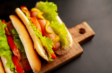 three hot dogs on a cutting board against a background of stone