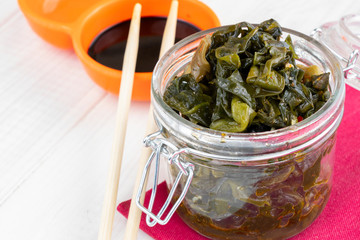 seaweed salad in glass bowl on light wooden background