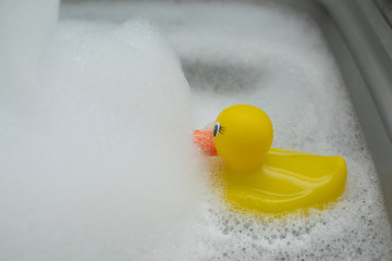 Happy yellow rubber duck having a bath in the bubble warm bath