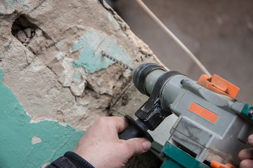 Repair and construction working indoors. Grunge background rubble and stones. Man's hands with a...