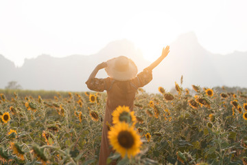 Fototapeta na wymiar Hipster woman traveler is enjoy travel into Sunflower field plantation during summer time vacation.