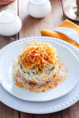 Salad with mushrooms, cucumbers and chicken, garnished with fried potato pie on a white plate, selective focus