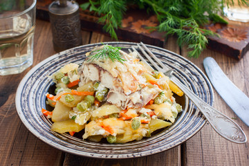 Baked mackerel with vegetables - potatoes, carrots, onions, green peas in a plate, selective focus