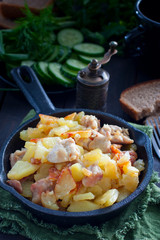 Fried potatoes with chicken on a cast-iron pan, selective focus