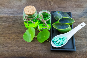 Slice Aloe Vera (Aloe barbadensis Mill.,Star cactus,  Aloin, Jafferabad or Barbados)   Aloe vera essential oil ,Green Asiatic Pennywort colorful pill  in spoon  on wooden