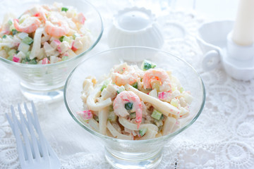 Salad with seafood: squid, shrimp, crab sticks in glass salad bowls, horizontal