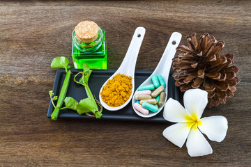 Spa herbal (white frangipani flowers, turmeric powder in white spoon ,pill,Cissus Quadrangularis Linn,pine,Aloe vera essential oil ) on wooden background