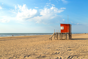 Beach scene. Red lifeguard tower in foreground. Beautiful morning of summer. The sun bright over...