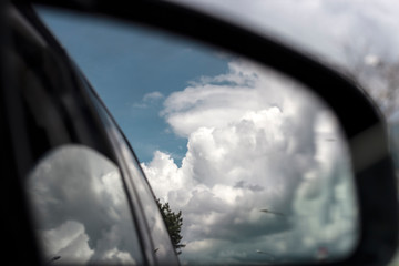 view of cloudy sky from the rear view mirror of a car