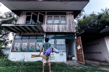 Poor man and mat with pillow stand on old wooden house with Thai style in black  tone