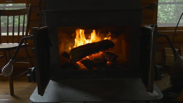 Fire burning in wood stove. Interior cottage setting. Ontario, Canada.