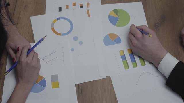Shot of graphic data templates table with business people analyzing growth rates and trends. Above view. Workplace. Office space.