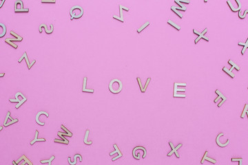 Wooden ABC alphabet letters on pink background.Love word written with wooden letters