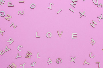 Wooden ABC alphabet letters on pink background.Love word written with wooden letters