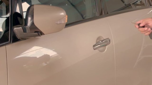 The thumb is pressing the car remote key go to the car. Side mirror spread out.And use the hand to open the door.