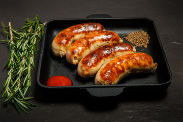square pan with fried sausages, ketchup, caraway and rosemary