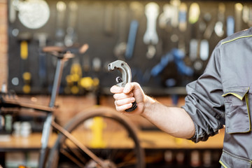 Repairman holding tube cutter for bicycle helm in the workshop, close-up view