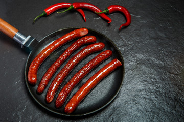 top view on round pan with five long fried hunting sausages