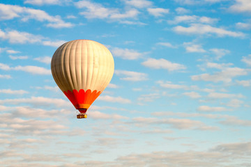 Naklejka premium Hot air balloon in blue cloudy sky