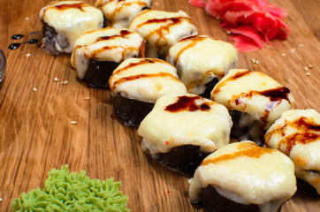 Unusual sushi rolls on a wooden table. Ukrainian sushi rolls with baked cheese and crabs