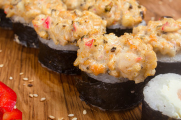 Unusual sushi rolls on a wooden table. Ukrainian sushi rolls with baked cheese and crabs