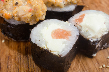 Unusual sushi rolls on a wooden table. Ukrainian sushi rolls with baked cheese and crabs