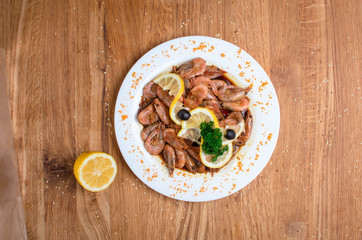 Appetizing shrimps in soy sauce on a white dish. Shrimps with olives and lemon. Restaurant seafood...