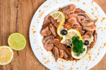 Appetizing shrimps in soy sauce on a white dish. Shrimps with olives and lemon. Restaurant seafood...