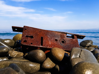rusty metallic mechanism on top of the stones on the shore