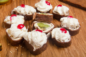 Sweet rolls made of pancakes filled with fruit and covered with cream and jam. Sweet breakfast Delicious dessert