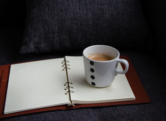 The ceramic coffee cup put on the opened book,blurry light around
