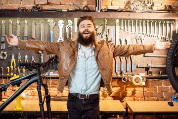Portrait of a young stylish businessman as a shop owner standing at the bicycle workshop