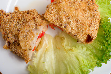 Chicken breast in sesame deep-fried. Chicken fillet stuffed with cheese and bell pepper. Restaurant dish on a white plate
