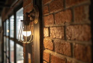 Antique electronic lamp, hang at the red brick wall in the restaurant.soft focus.