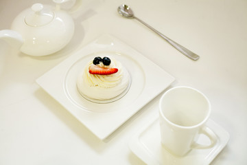 Anna Pavlova cake on a white plate with a white tea set