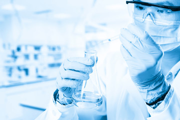 Laboratory beaker in analyst's hand in plastic glove